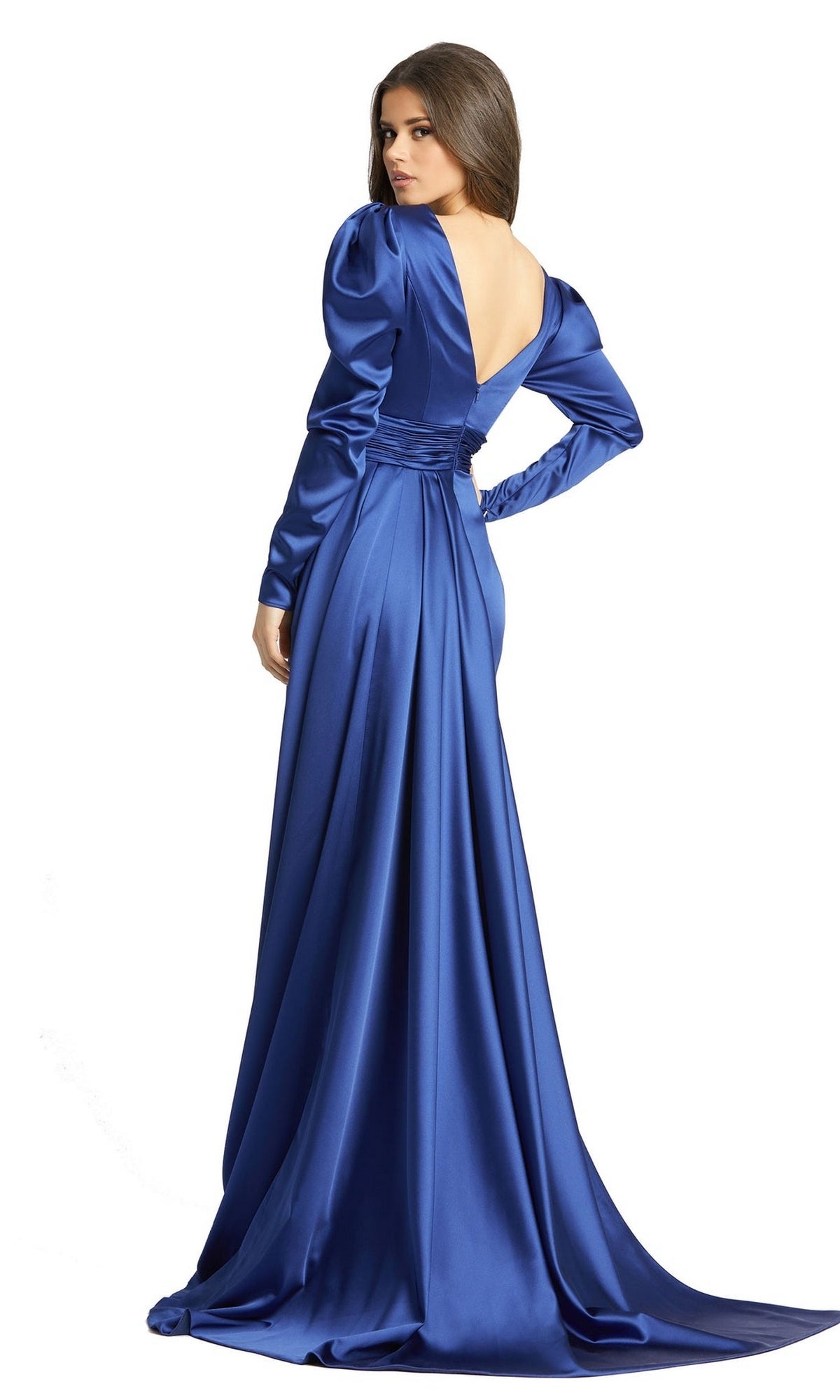 A woman in the Long Formal Dress 12404 by Mac Duggal, featuring long sleeves, royal blue satin fabric, a V-neck, and an open back, stands and looks over her shoulder.